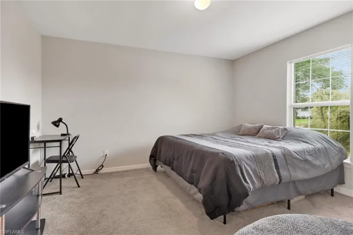 Bedroom with light colored carpet and an office area