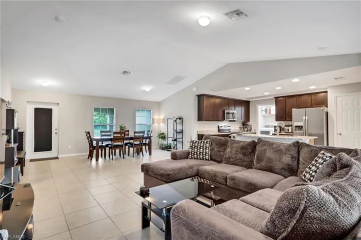 Living area with lofted ceiling, light tile patterned floors, and recessed lighting
