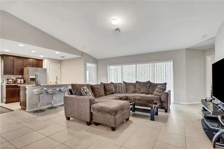 Living room featuring lofted ceiling, light tile patterned flooring, and recessed lighting
