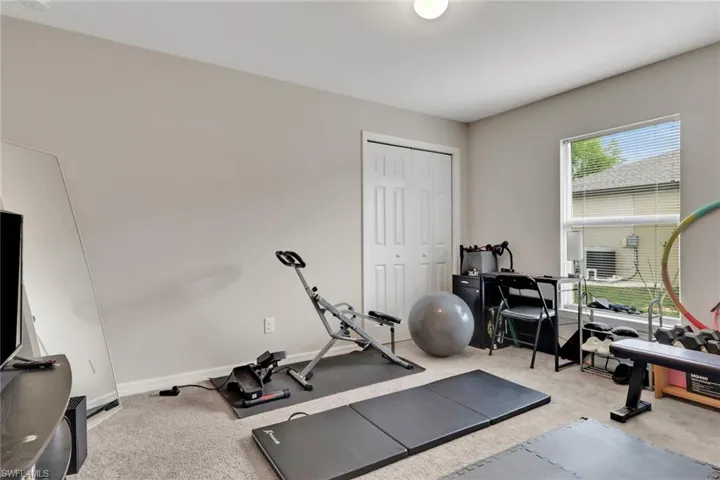 Exercise area featuring light carpet and baseboards