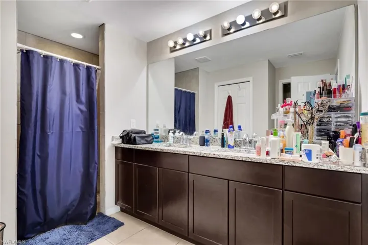 Full bathroom featuring a shower with shower curtain, vanity, and light tile patterned flooring