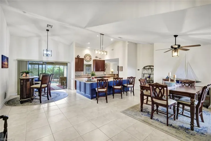 Dining area featuring high vaulted ceiling, light tile patterned flooring, recessed lighting, a chandelier, and ceiling fan