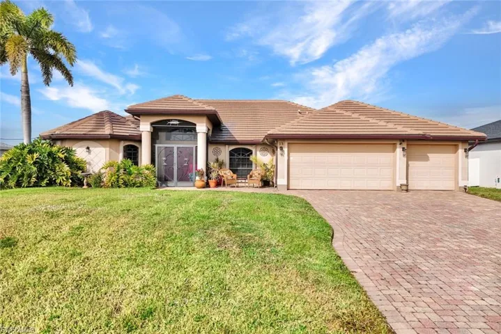 View of front of house featuring stucco siding, decorative driveway, a garage, and a front lawn