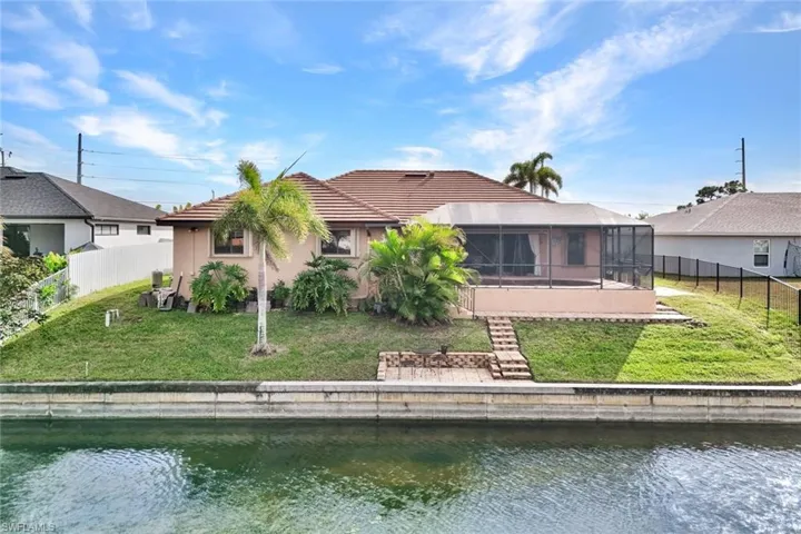 Rear view of house featuring a fenced backyard, a sunroom, a water view, stucco siding, and a tiled roof