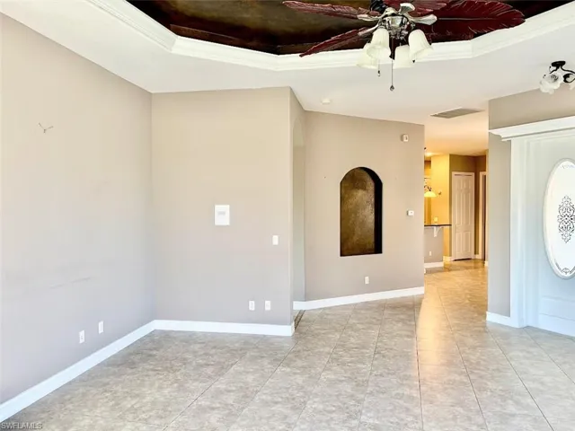 Tiled spare room with ceiling fan, a raised ceiling, and ornamental molding