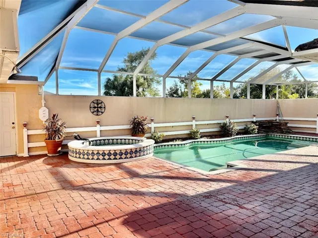 View of swimming pool featuring glass enclosure and a patio