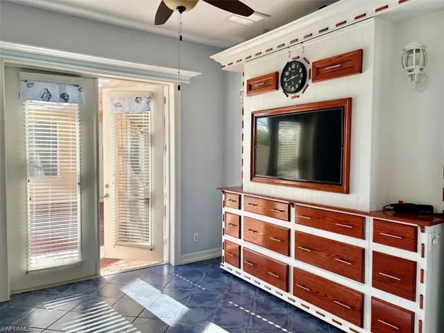 Doorway featuring dark tile patterned flooring, a wealth of natural light, and ceiling fan