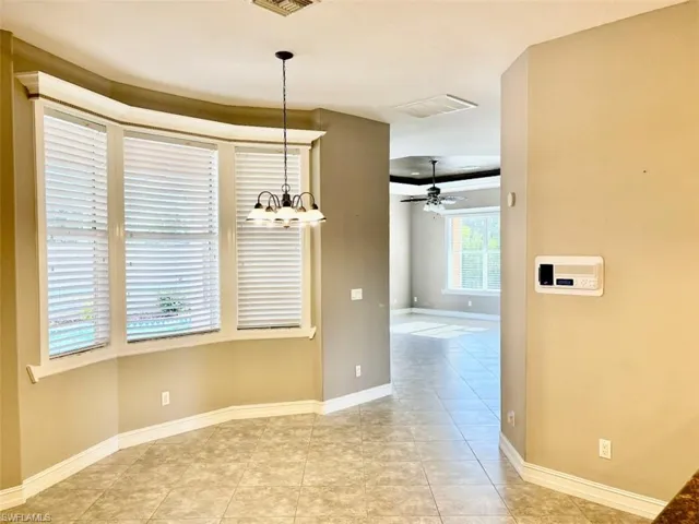 Unfurnished dining area with ceiling fan with notable chandelier and light tile patterned flooring