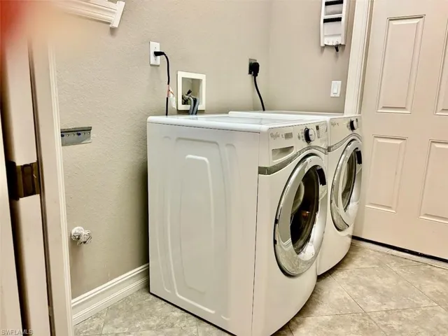 Clothes washing area with washer and clothes dryer and light tile patterned floors