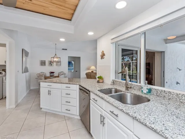 Kitchen featuring dishwasher, white cabinetry, a tray ceiling, and a sink