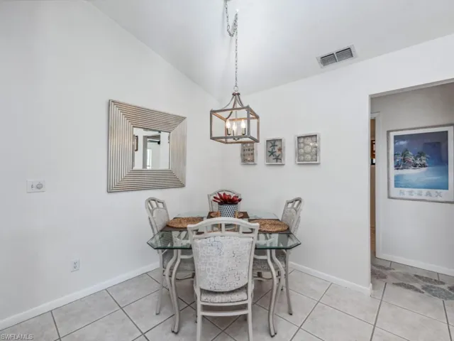 Tiled dining area featuring a notable chandelier and lofted ceiling