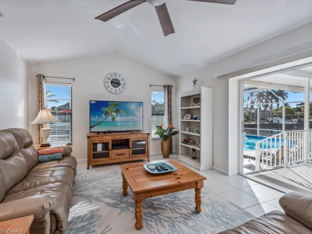 Tiled living room featuring ceiling fan, lofted ceiling, and a wealth of natural light