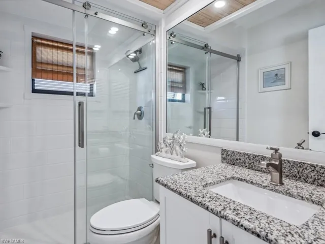 Bathroom featuring walk in shower, vanity, wood ceiling, and toilet