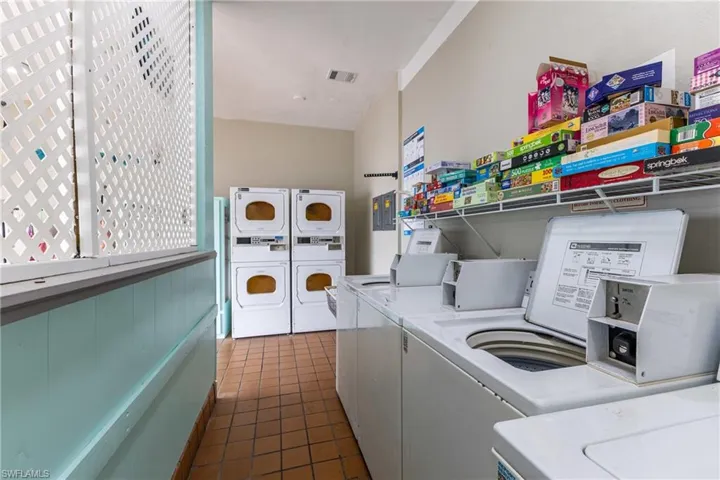 Shared laundry with washing machine and clothes dryer and dark tile patterned flooring