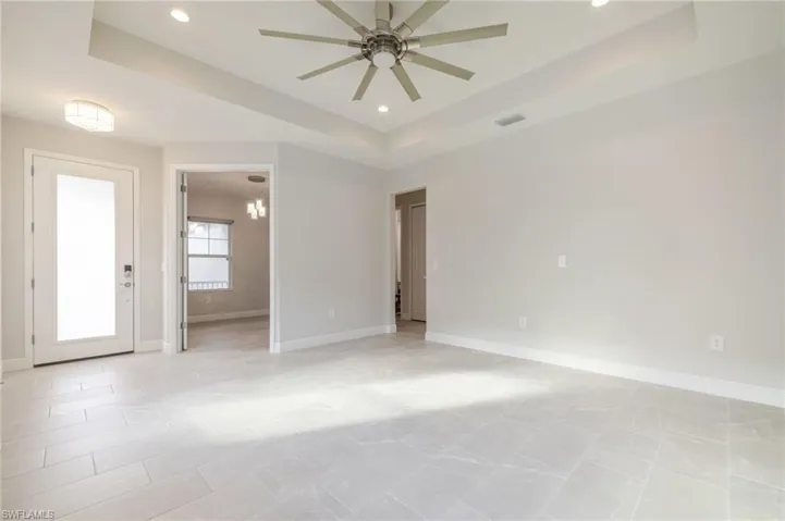 Unfurnished room featuring a tray ceiling, recessed lighting, ceiling fan, and a chandelier