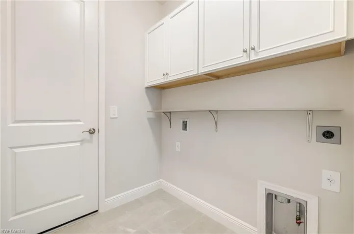 Laundry area with cabinet space, hookup for a washing machine, light tile patterned floors, and hookup for an electric dryer