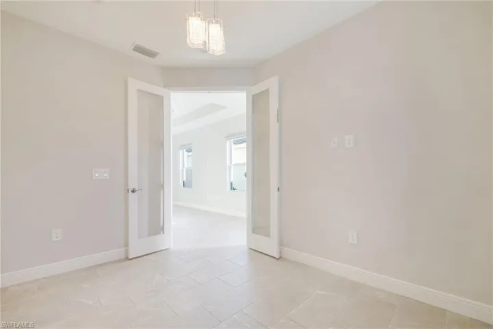 Empty room with french doors and light tile patterned floors