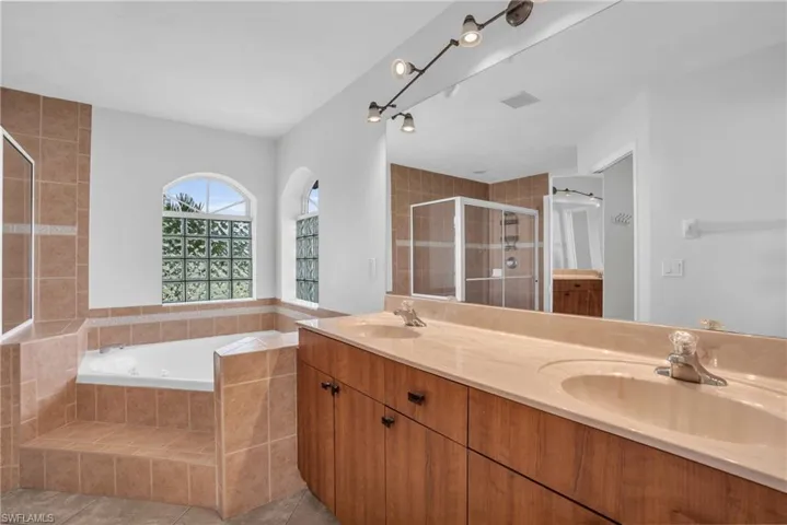 Bathroom featuring dual vanity, shower with separate bathtub, and tile patterned floors