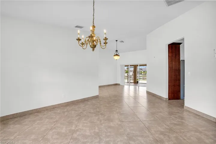 Unfurnished room featuring a high ceiling, light tile patterned floors, and an inviting chandelier
