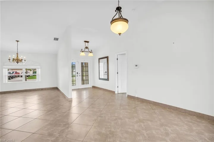 Foyer with lofted ceiling, a notable chandelier, and light tile patterned floors