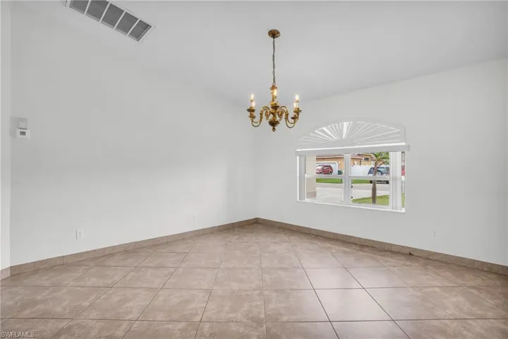 Tiled spare room featuring a chandelier