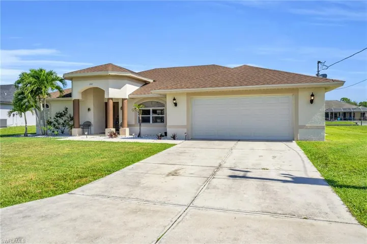 View of front of property with a garage and a front lawn
