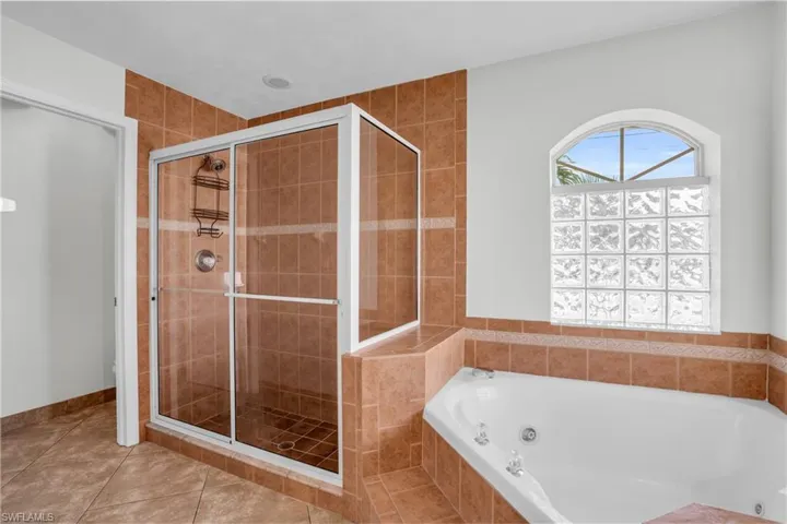 Bathroom with shower with separate bathtub and tile patterned flooring