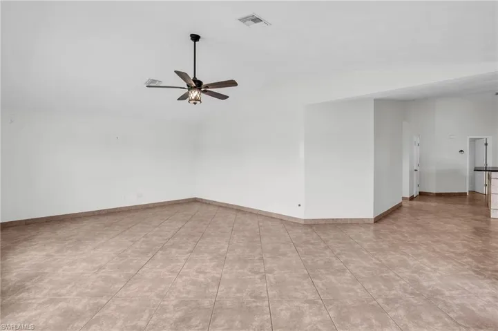Tiled spare room featuring lofted ceiling and ceiling fan