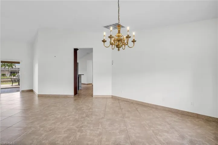 Tiled spare room featuring an inviting chandelier