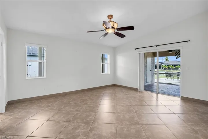 Unfurnished room featuring light tile patterned flooring, lofted ceiling, and ceiling fan