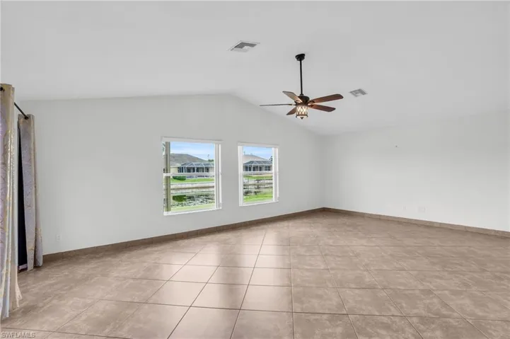 Unfurnished room featuring ceiling fan, lofted ceiling, and light tile patterned floors