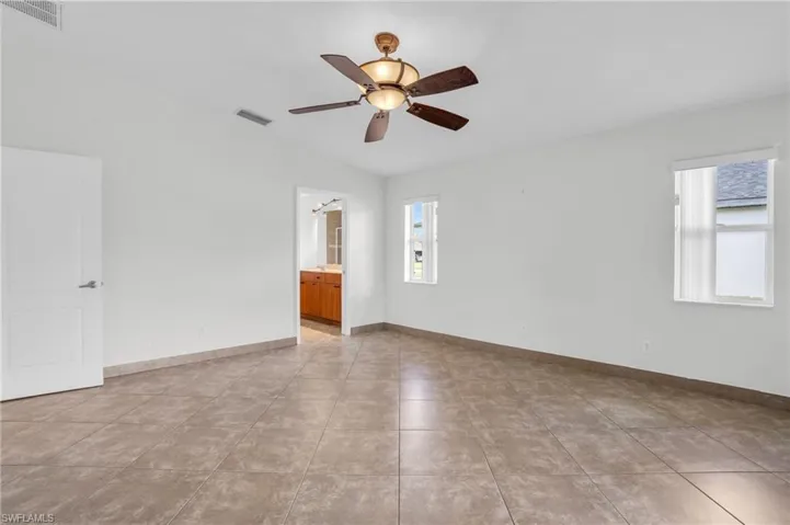 Tiled spare room featuring ceiling fan