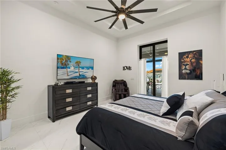 Bedroom with access to outside, marble look tile flooring, a tray ceiling, and ceiling fan