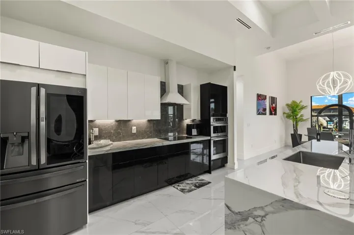 Kitchen with appliances with stainless steel finishes, modern cabinets, white cabinetry, dark cabinets, and wall chimney range hood