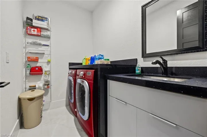 Laundry room with washer and clothes dryer, light marble finish floors, and a textured wall