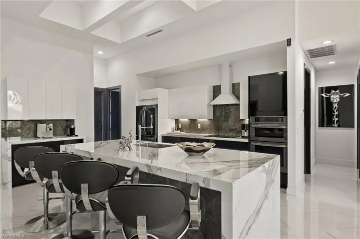 Kitchen featuring white cabinets, modern cabinets, a breakfast bar area, light stone countertops, and recessed lighting