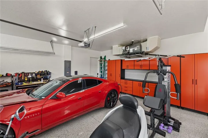 Garage featuring electric panel, heating unit, and a garage door opener