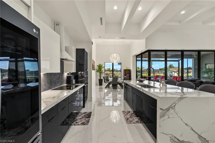 Kitchen with modern cabinets, light stone countertops, pendant lighting, a high ceiling, and beamed ceiling