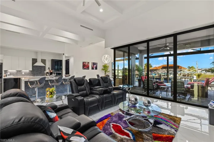 Living room featuring a ceiling fan, coffered ceiling, beam ceiling, and a high ceiling