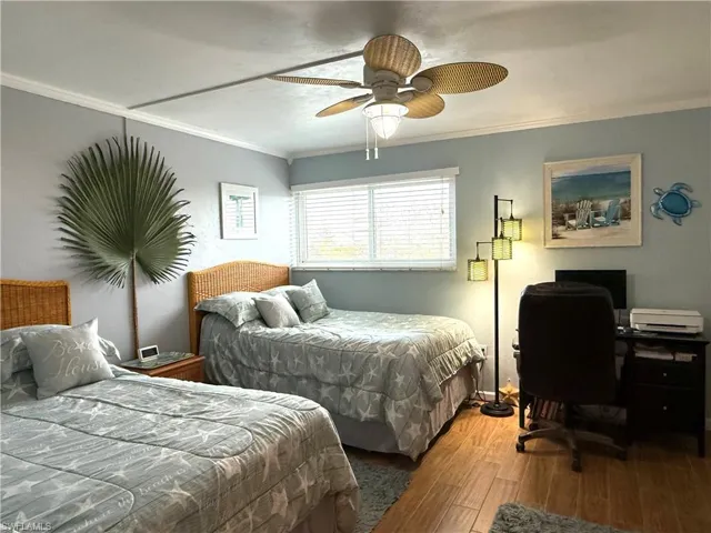 Bedroom featuring wood finished floors, crown molding, and a ceiling fan