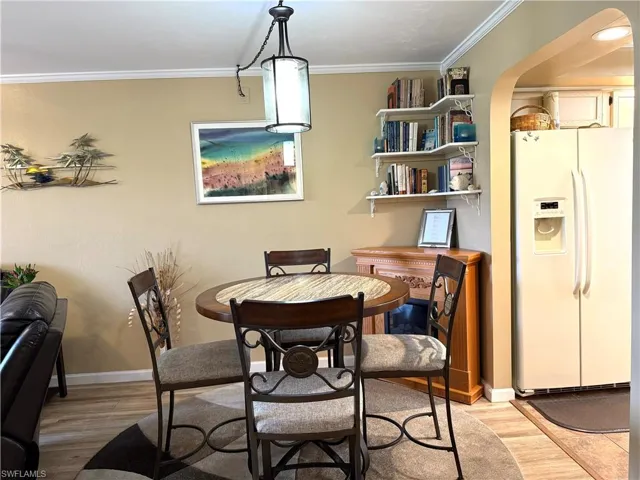 Dining room with crown molding, light wood finished floors, and arched walkways