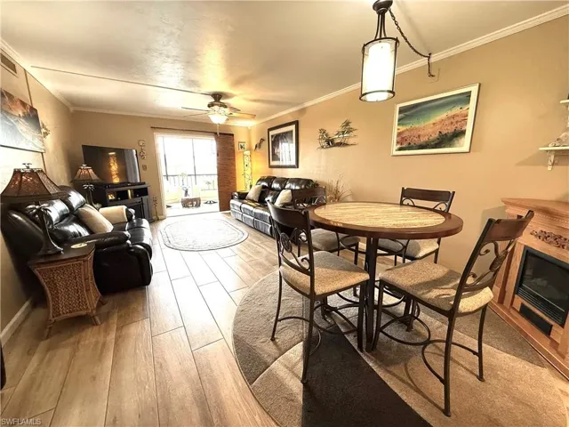Dining room with light wood-style flooring, ornamental molding, and ceiling fan