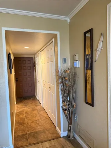 Corridor featuring crown molding and a textured wall