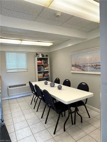 Dining room with a drop ceiling, a wall unit AC, and light tile patterned flooring