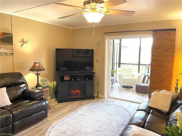 Living room with wood tiled floors, crown molding, and ceiling fan