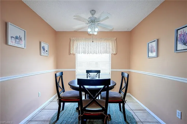 Tiled dining space featuring ceiling fan and a textured ceiling