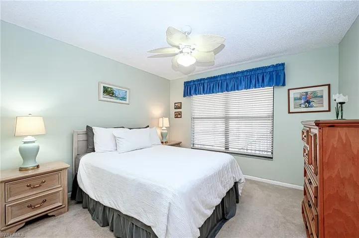 Carpeted bedroom with ceiling fan and a textured ceiling