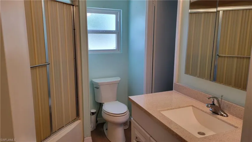 Full bathroom featuring vanity, toilet, and shower / bath combination with glass door