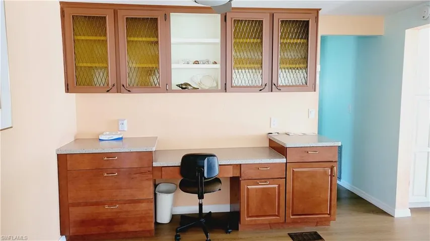Office area with built in desk, wood finished floors, and baseboards