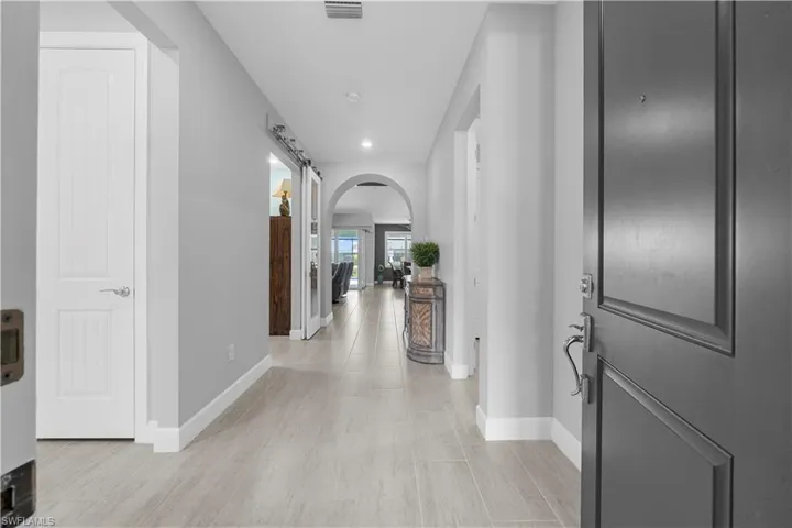 Gorgeous Entrance Foyer with Beautiful Arch entry to the Main Living area. Take notice of the Sliding Barn Doors. Grey Plank Tile throughout the home. 16160 Bluestem Ln. Babcock Ranch, FL 33982